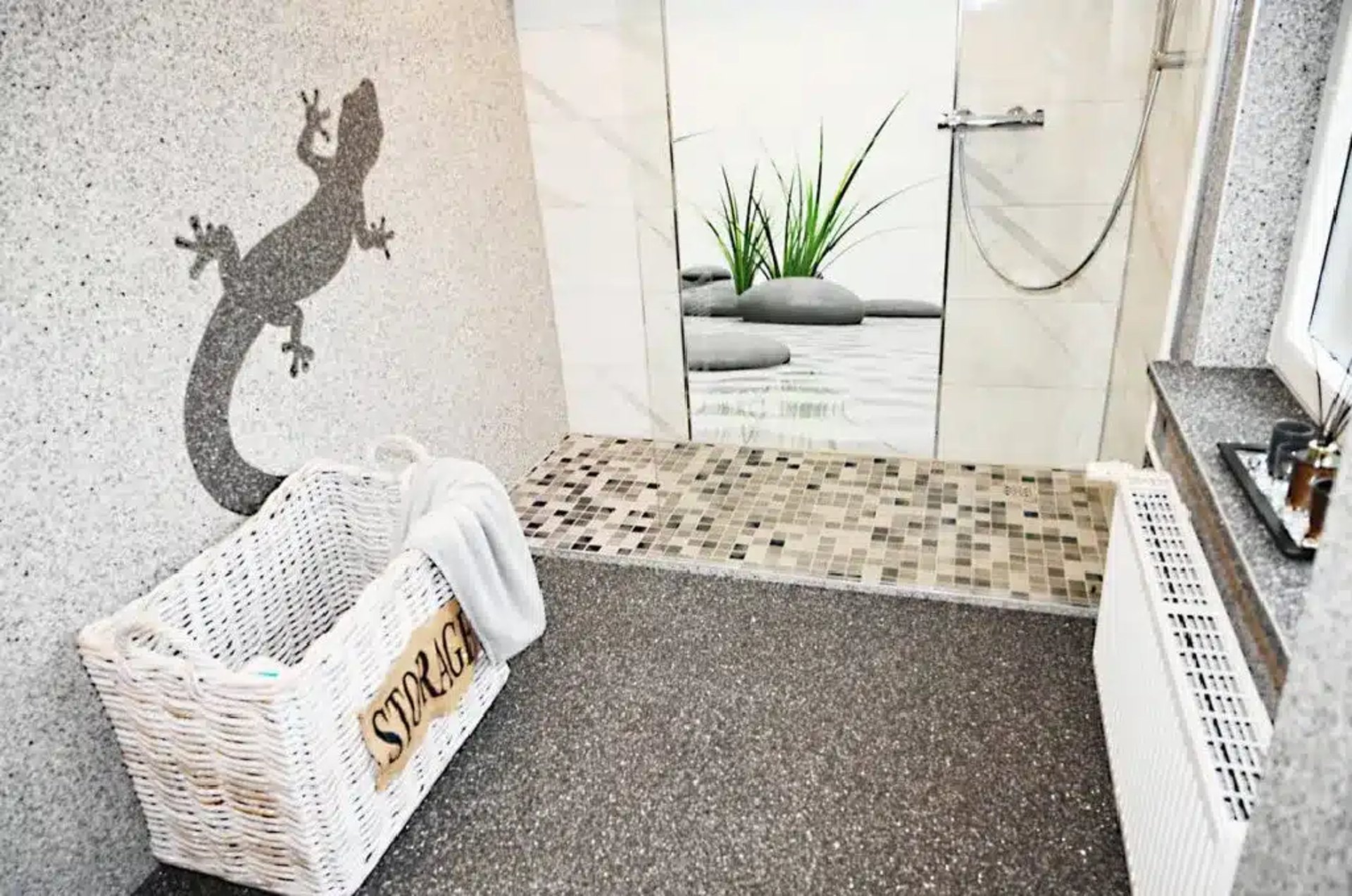 Badezimmer mit Steinteppich und einer Eidechse an der Wand